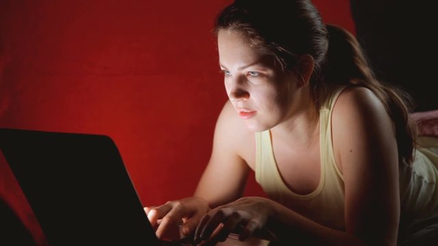 девушка вечером общается в социальных сетях лежа на диване