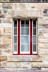 Fototapeta na wymiar Sandstone wall with red framed window
