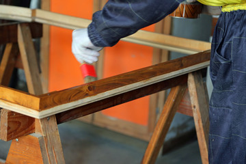 Carpenter worker during painting  of an old wooden frame