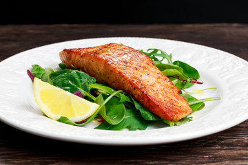 Fried salmon fillet served with vegetables and lemon