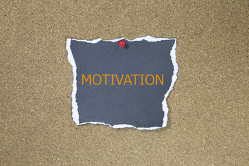 motivation in text on sticky note posted to a cork notice board.