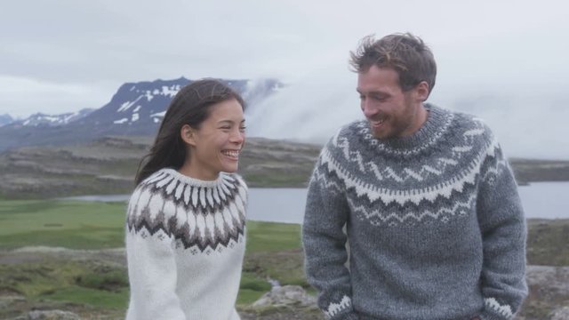 Happy young couple laughing outside in nature playful. Couple having fun on Iceland joyful and playful wearing Icelandic sweaters. Woman and man model enjoying nature landscape.  RED EPIC 96 FPS