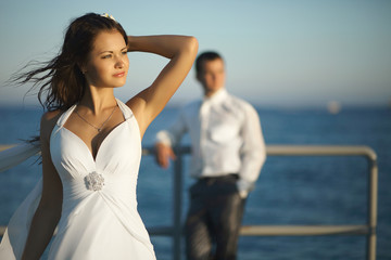 Gorgeous wedding couple standing on pier under spray, splashes a