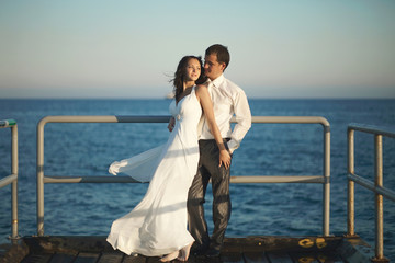 Gorgeous wedding couple standing on pier under spray, splashes a