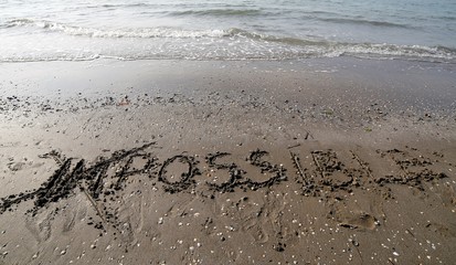 IMPOSSIBLE with the letters IM cancelled in the sand of the beac