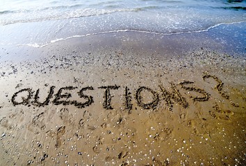 Questions with question mark written on the sand of the sea in s