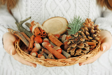Wicker basket with Christmas decoration in woman hands, closeup