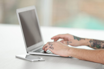 Young man with tattoo using laptop at the table