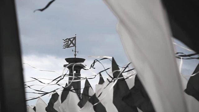 Black and white flags sway on wind in summer day. Cloudness sky before rain. Column with flag. Slow motion. 
