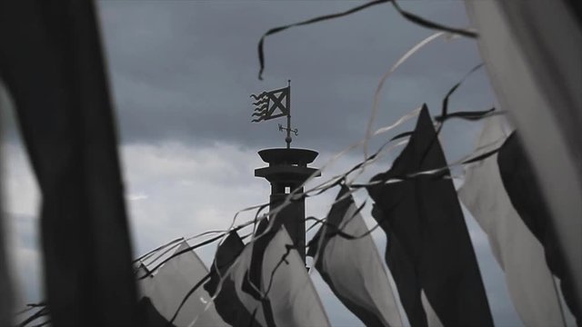Black and white flags sway on wind in summer day. Cloudness sky before heavy rain. Column with flag. Slow motion. 