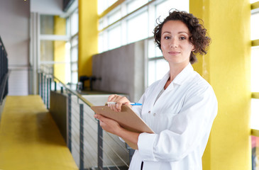 Portrait of a female doctor holding her patient chart in bright modern hospital