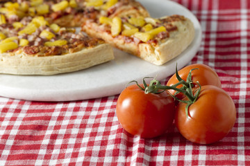 hawaiian pizza and a whole ripe tomato