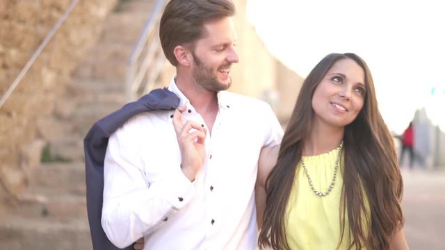 4k footage, happy young couple walking along ancient wall, enjoying sightseeing trip on sunny day
