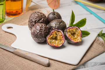 Passion fruits on white ceramic tray on wooden table background.