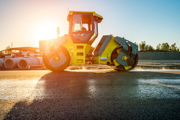 Sunset above the road roller working on the construction site