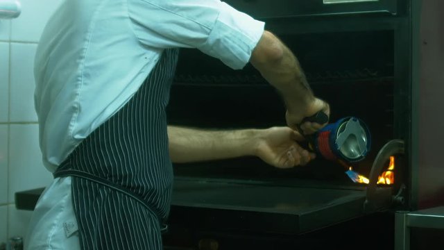 Restaurant chef kindles coals with a burner. 120 FPS slow motion shot. Blackmagic URSA Mini