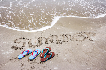 Fototapeta na wymiar Slippers with summer handwritten on the beach