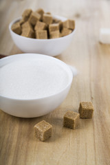 Cane and white sugar in a white bowls on the table