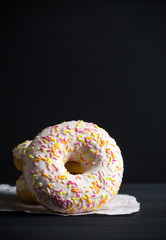 Donut with sprinkles on the black background