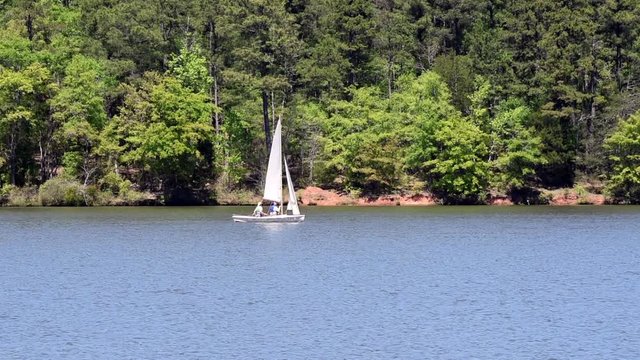 Small Sailboat Crosses left to Right on lake in early spring