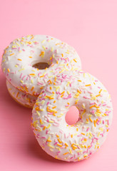 Donut with sprinkles on the pink background