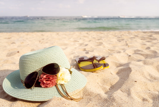 Summer vacation concept with straw hat, sunglasses and flip flops on sandy tropical beach - vintage color styles