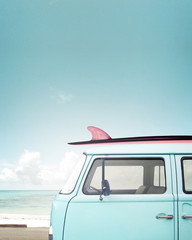 Vintage car parked on the tropical beach (seaside) with a surfboard on the roof