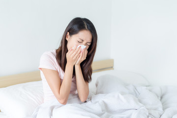 Sick woman blowing lying on her bed at home