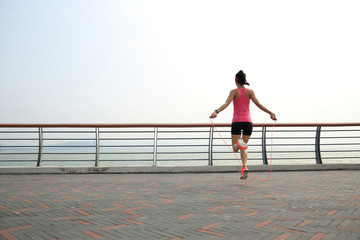 young fitness woman jumping rope at seaside
