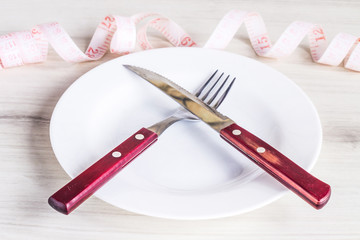 empty plate with cutlery and a measuring tape