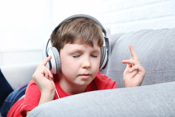 Portrait of young boy with headphones on grey sofa