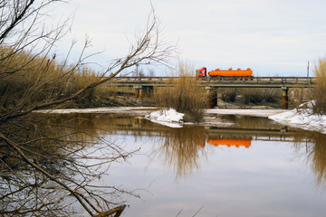Obraz premium Truck driving on bridge over a river in the spring.