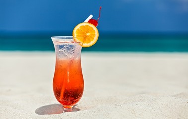 Glass of cocktail is on sandy coral  beach