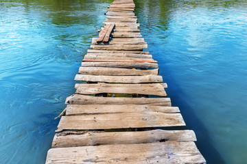 Old wooden bridge through the river