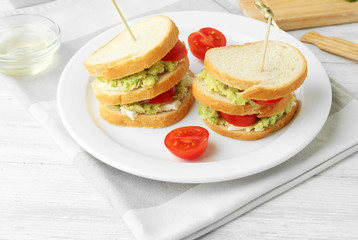 Vegetarian avocado sandwich on a white plate.