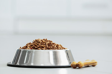 Pet food in a metal bowl on a floor.