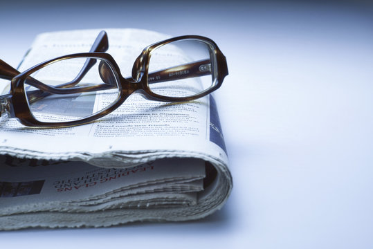 Glasses on newspaper, blue tone