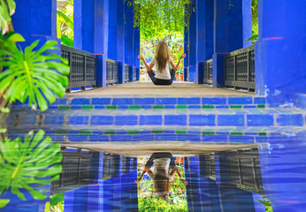 Young girl doing yoga and relaxing in the alcove with reflection in water.