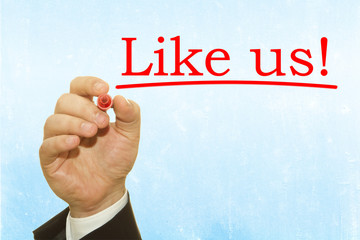 Businessman hand writing Like Us message on blue background.