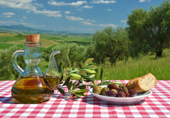 Oil and olives on the table against Tuscan landscape. Italy
