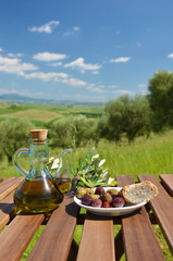 Oil and olives on the table against Tuscan landscape. Italy