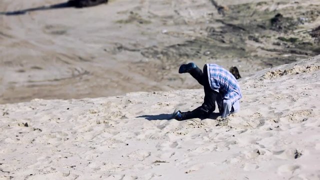 child tumbles into the sand