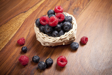 reife Blaubeeren und rote Himbeeren auf Holztisch Hintergrund