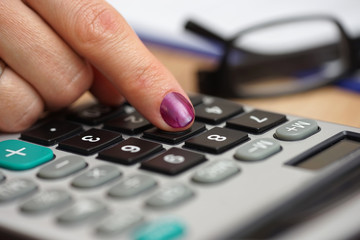 close up of a female woman pressing on calculator button with ey
