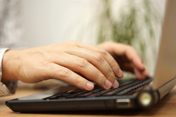 young adult is typing on laptop computer keyboard