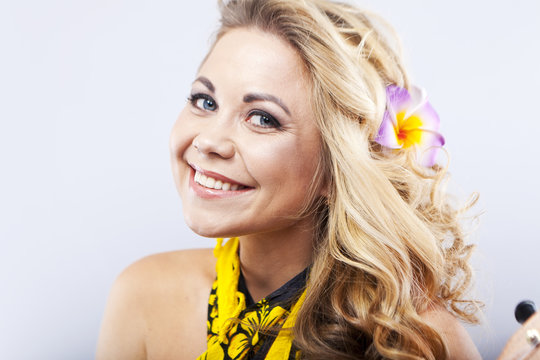 Cheerful young blonde in a Hawaiian scarf. Girl plays on ukulele. Hawaii style. Portrait of a smiling woman
