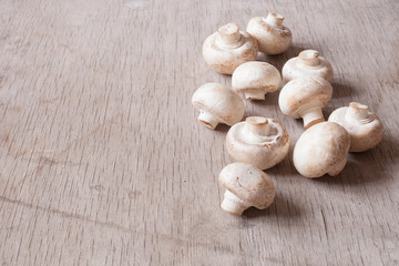 Fototapeta na wymiar White raw champignons closeup on a wooden background. Group of fresh mushrooms on a wooden table.