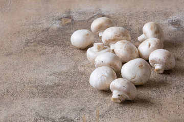 White raw champignons closeup on a wooden background. Group of fresh mushrooms on a wooden table.