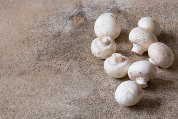 Fototapeta na wymiar White raw champignons closeup on a wooden background. Group of fresh mushrooms on a wooden table.
