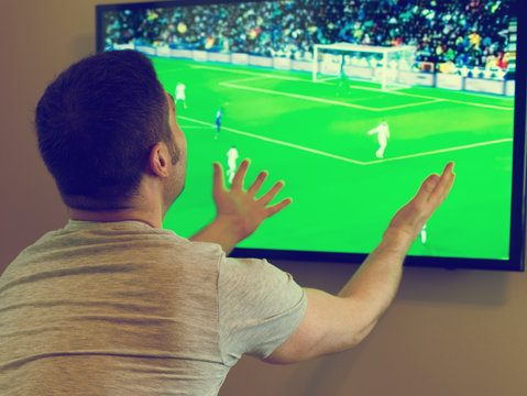 Man watching football match on television at home.